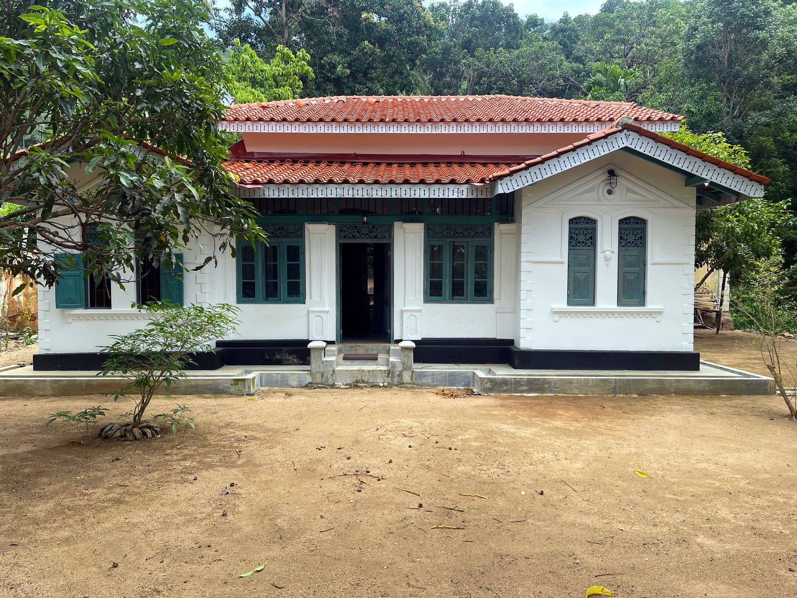 The front of Dadakire Walawwa in daylight, white walls and a terracotta tiled roof