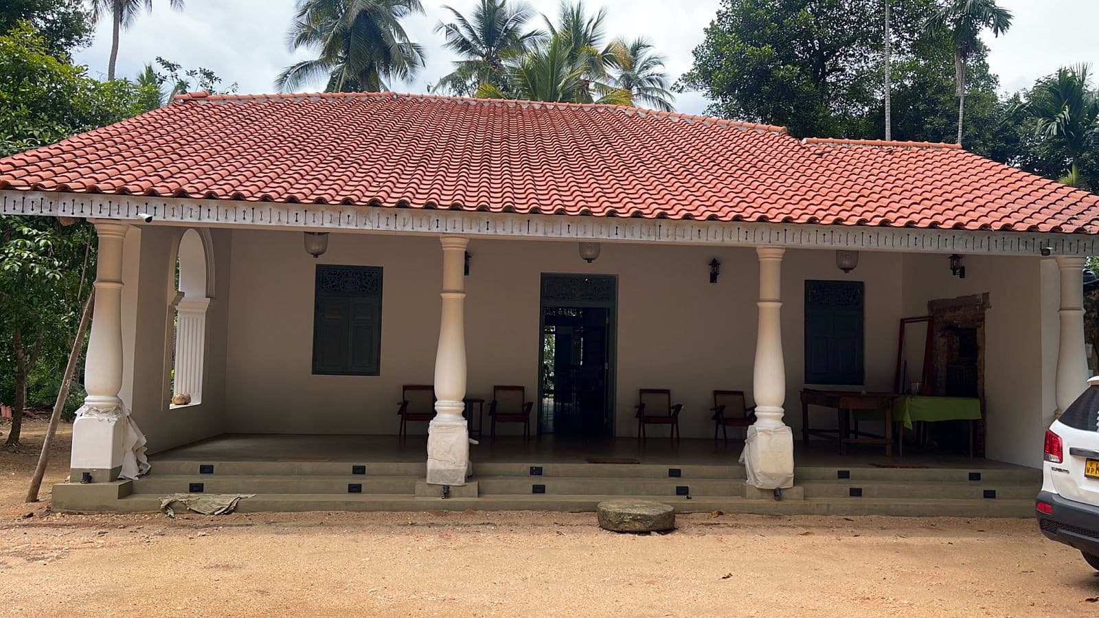 The front verandah by day, with white pillars and a tiled roof