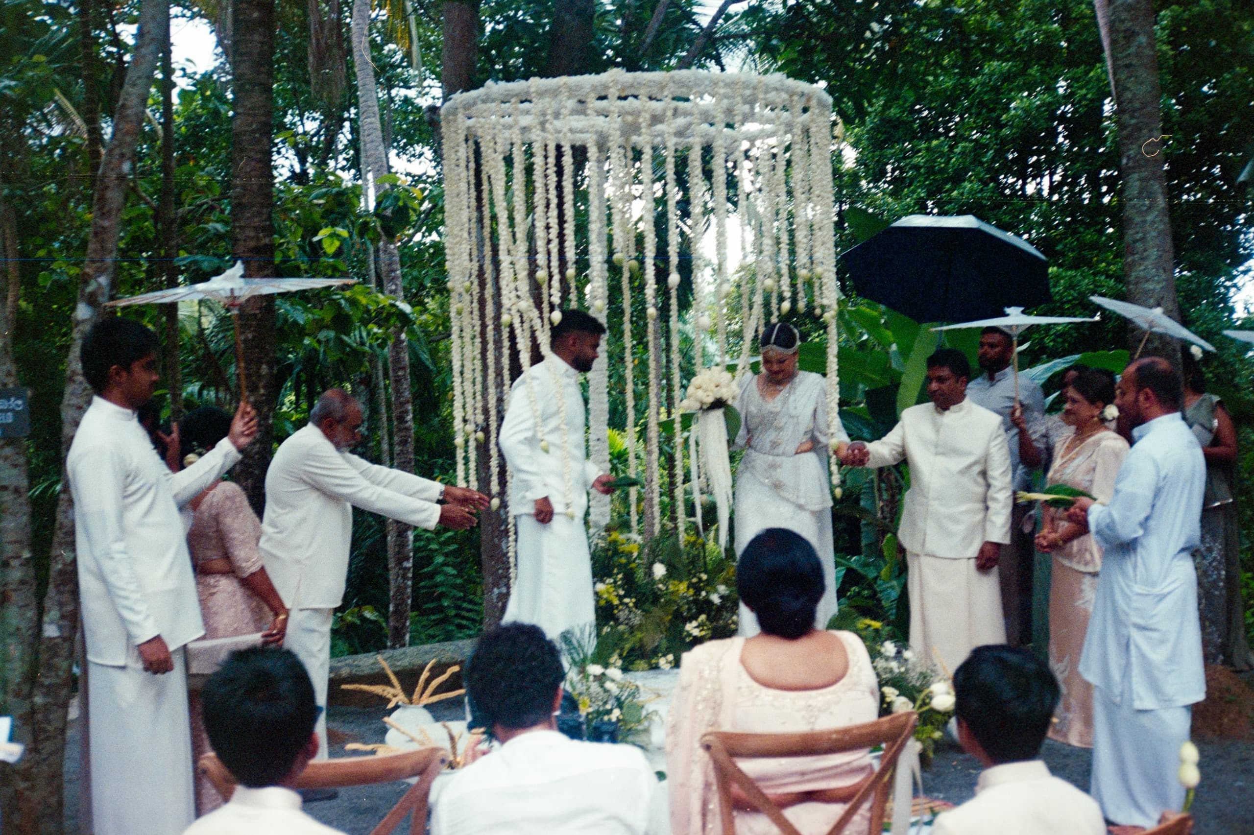A curtain of jasmine garlands hung between trees for a ceremony