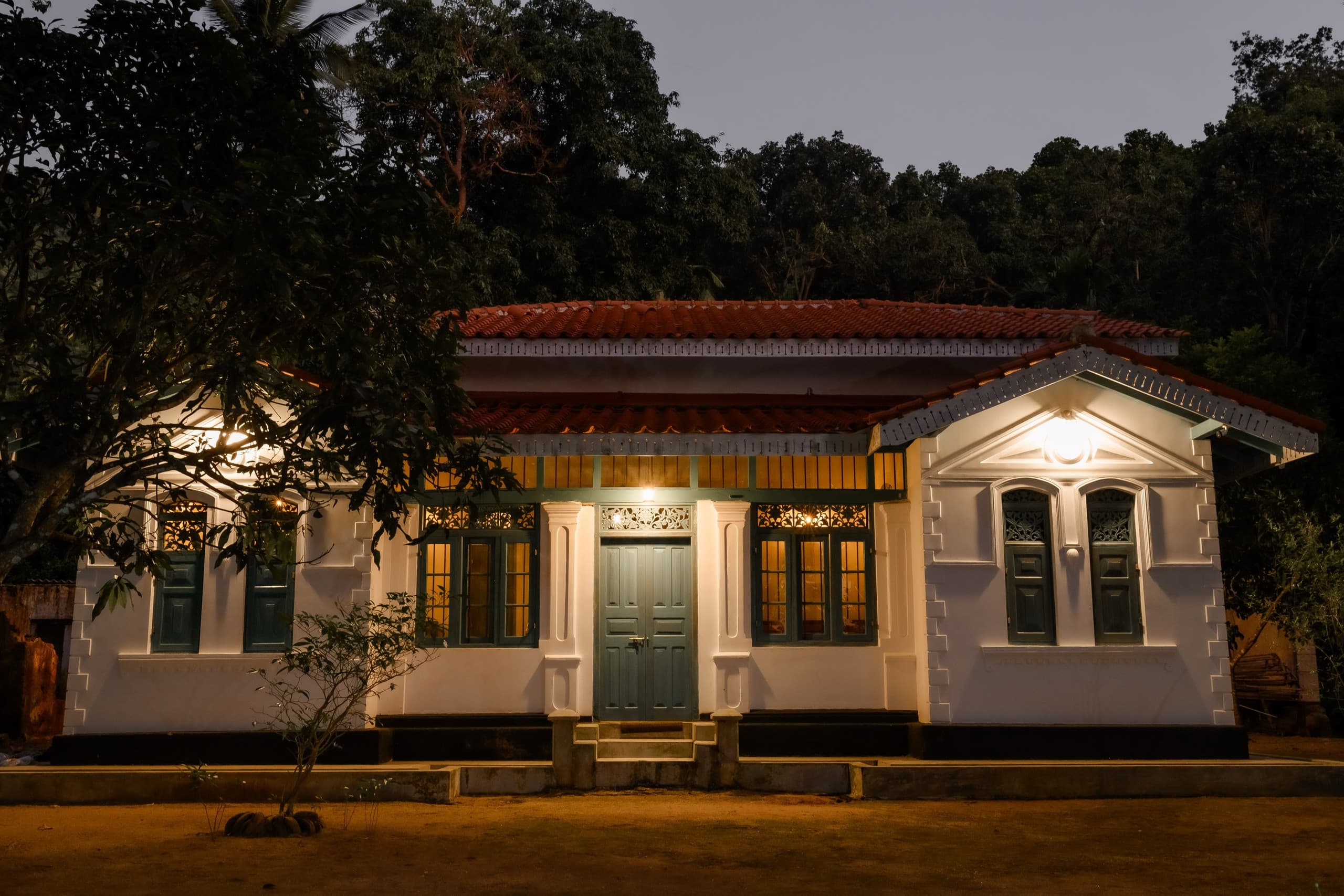 Gabled wing of the walawwa under trees at night